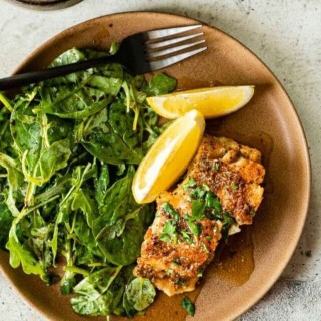 Close- up of Fish on a plate with salad and a slice of lemon