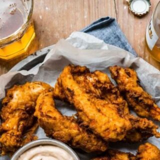 Chicken on a plate a with sauce and a beer
