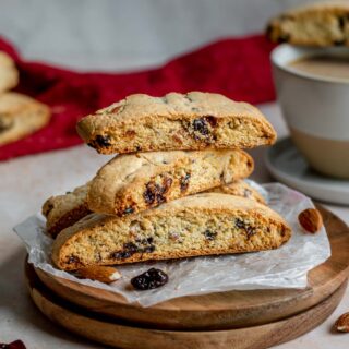 Cherry Almond Biscotti cookies stacked on plate with coffee cup in background