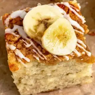 close up of moist buttery square treat with icing and slices of tropical fruit on top