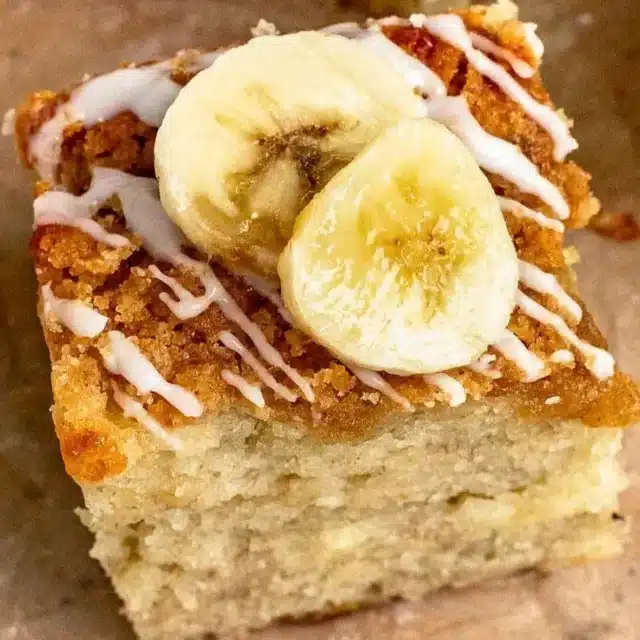 close up of moist buttery square treat with icing and slices of tropical fruit on top
