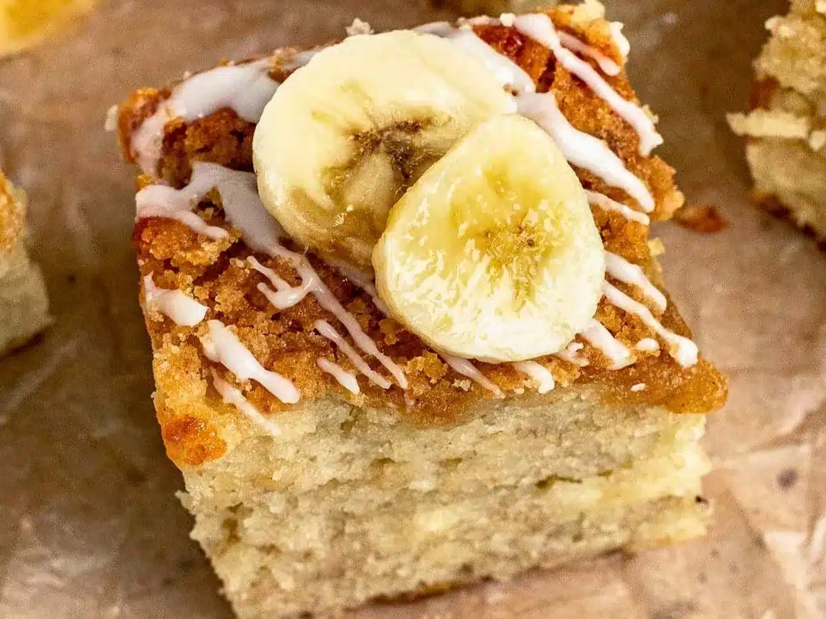 close up of moist buttery square treat with icing and slices of tropical fruit on top