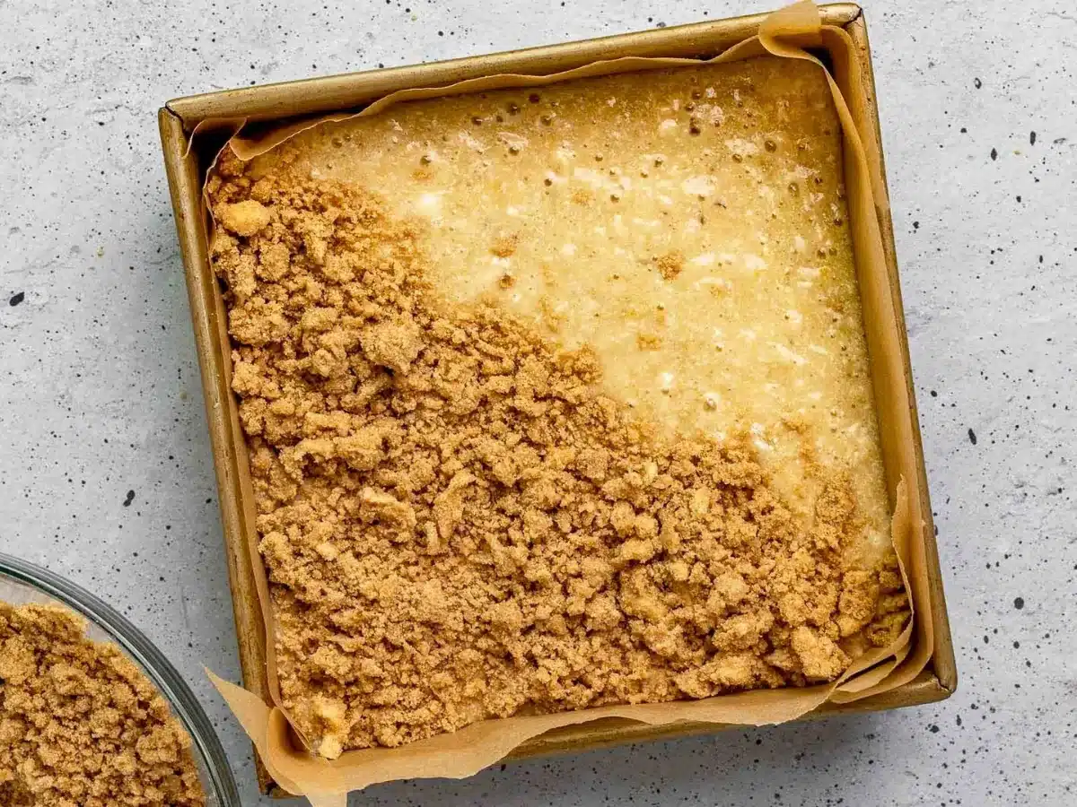 sweet buttery topping on top of mashed tropical fruit in a square baking pan