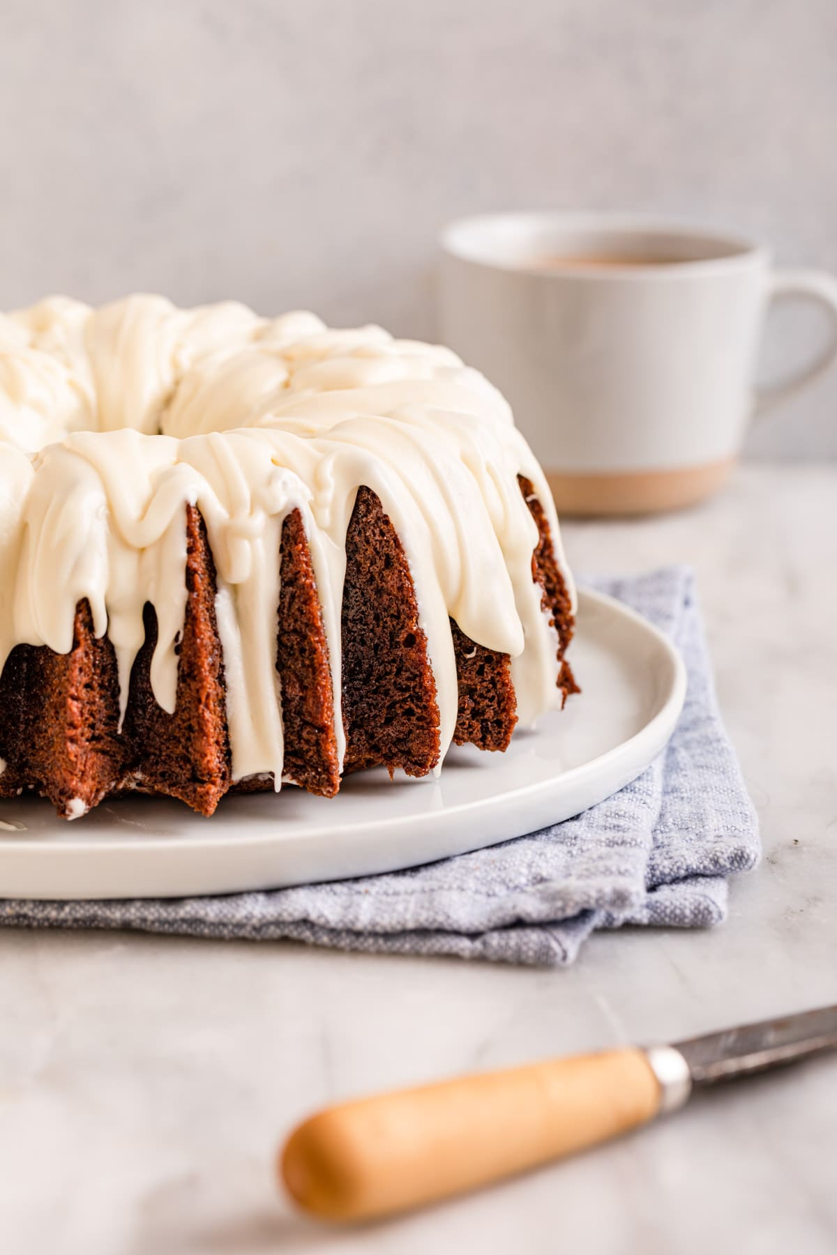 Banana Bundt Cake baked and frosted cake on plate, side view