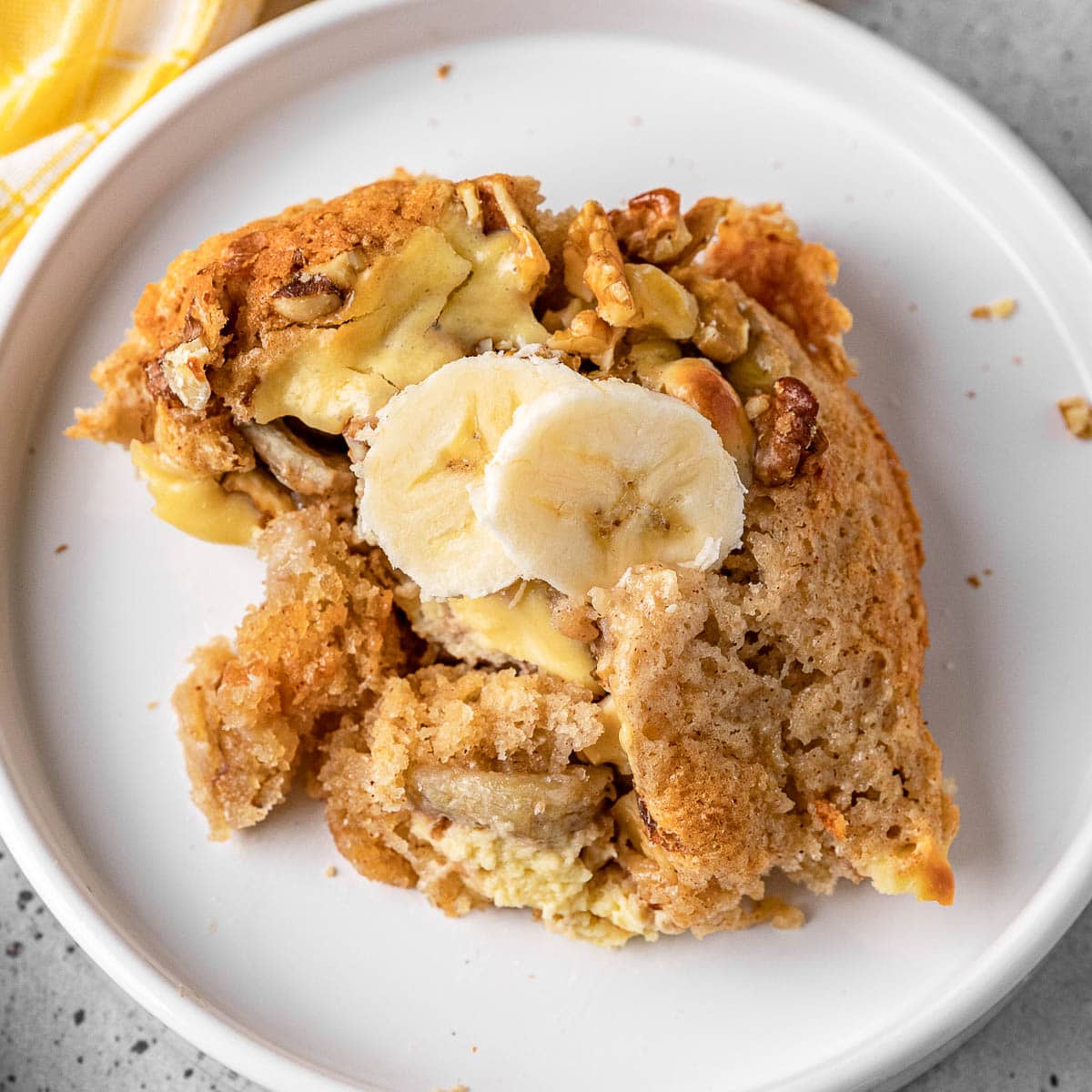 Bananas Foster Cobbler baked portion on plate with fresh banana slices on top