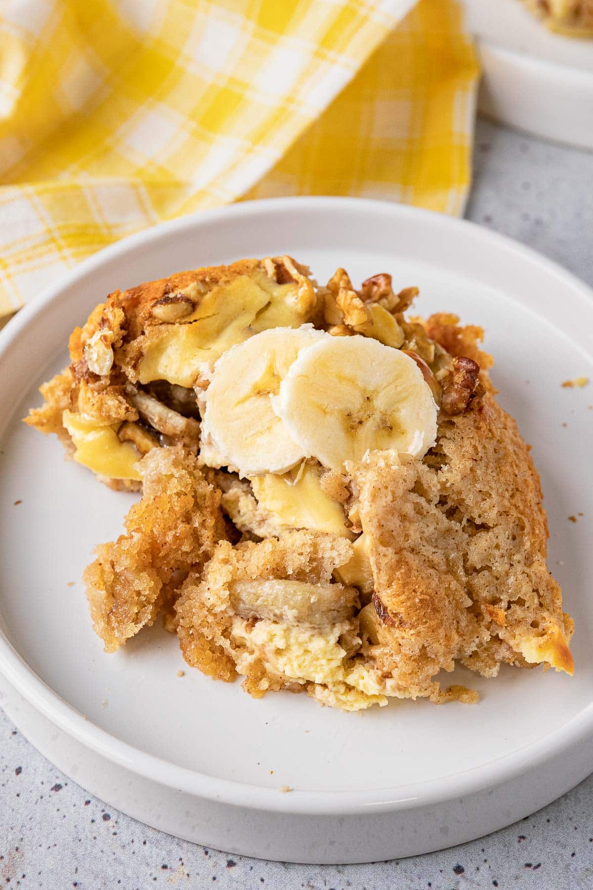 Bananas Foster Cobbler baked portion on plate with fresh banana slices on top