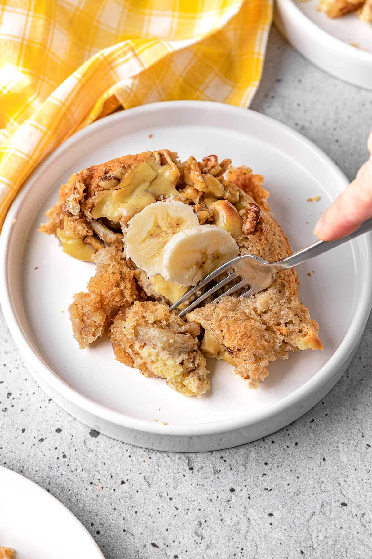 Bananas Foster Cobbler baked portion on plate cutting bite with a fork