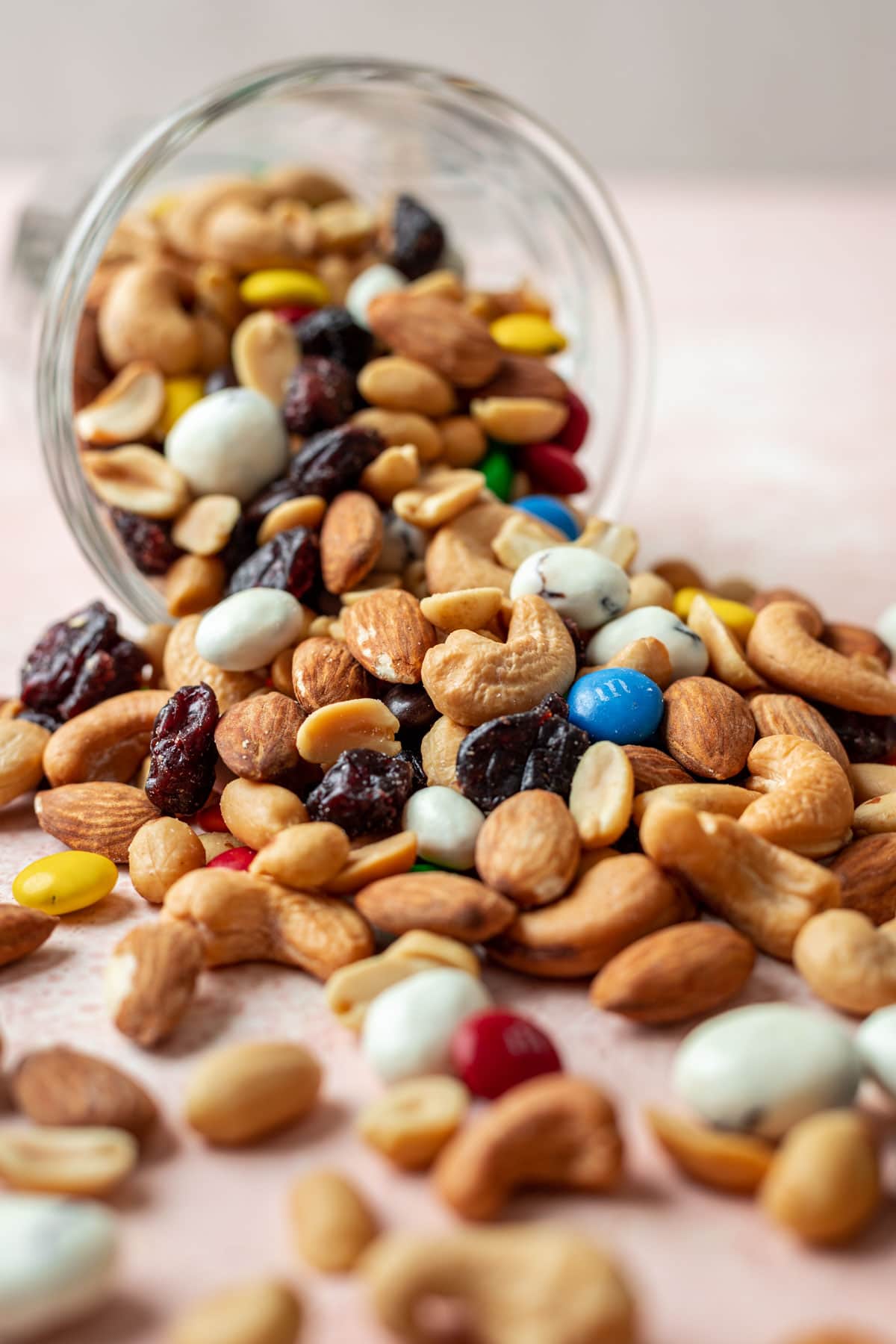 Classic Trail Mix combined spilling out of glass jar, side view close up