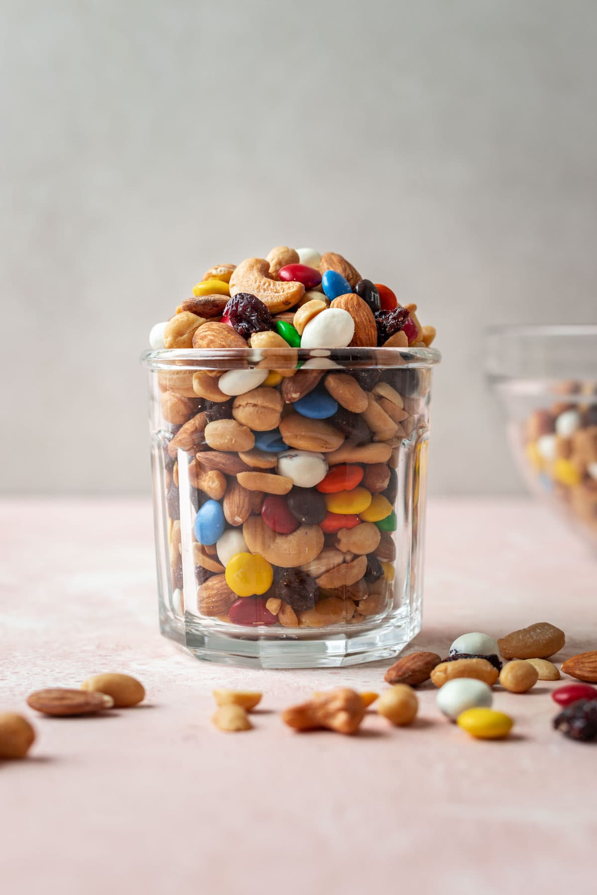 Classic Trail Mix combined in glass jar with some mix sprinkled around base, side view