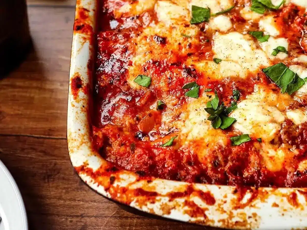 close up on baking dish with marinara, cheese, and garnishes