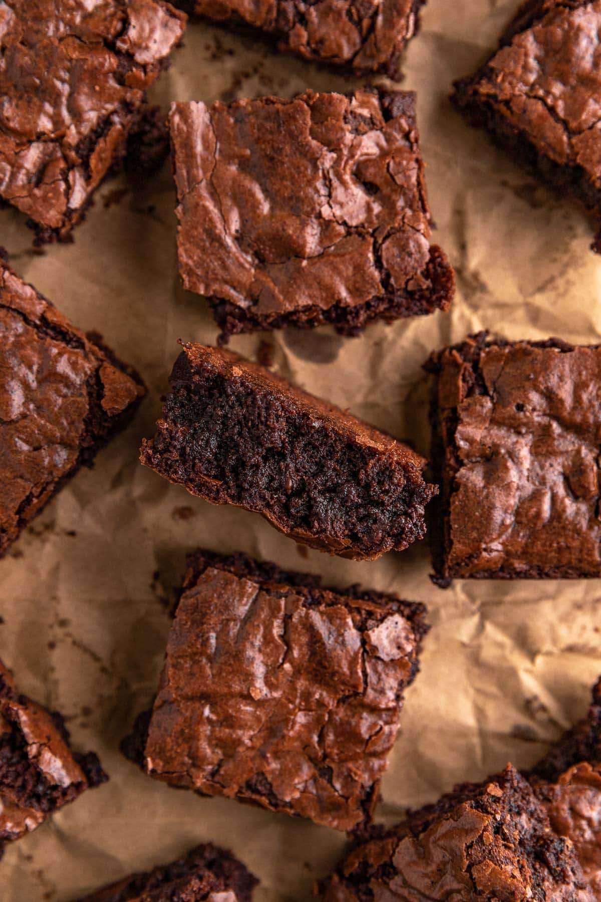 Super Rich Chocolate Brownies baked brownies spread out on parchment paper, one brownie on side
