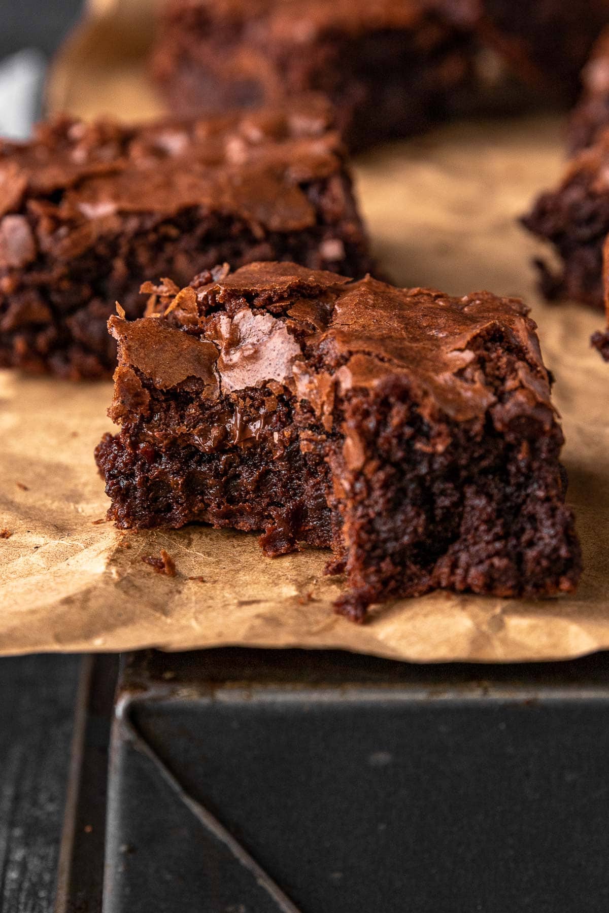 Super Rich Chocolate Brownies close up on a baked brownie on parchment paper with bite taken out