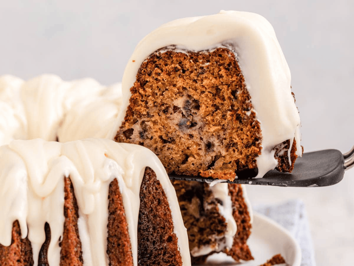 sliced frosted cake with spatula holding a slice up