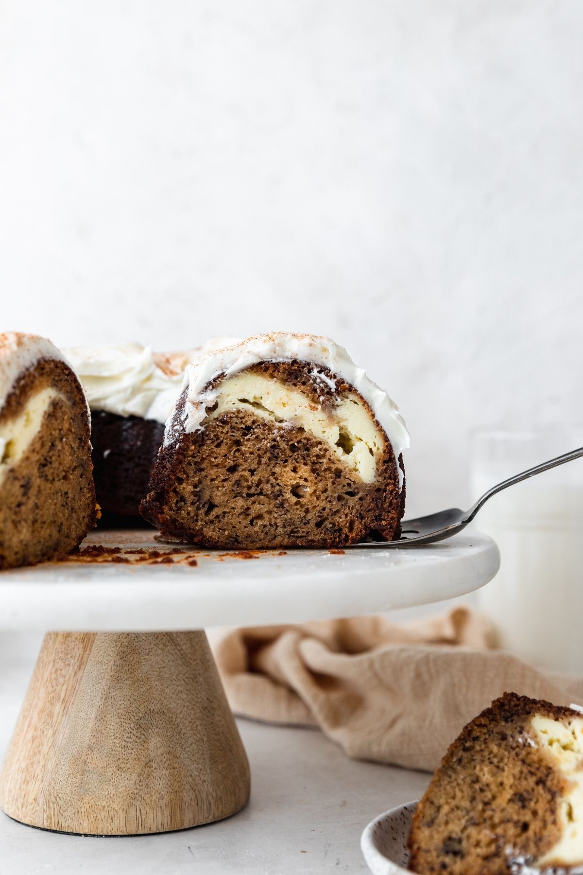 Banana Cheesecake Bundt Cake finished cake on stand with slice removed, side view