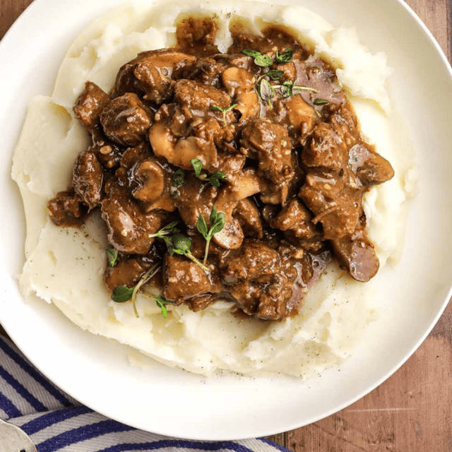 beef in gravy on top of mashed potatoes
