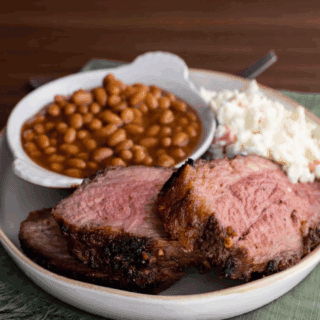 Up close view of a plate of roast, beans, and cole slaw