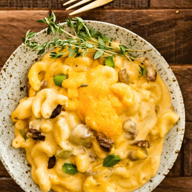 plate of elbow mac with cheese, meat, green peppers, and garnish on the side