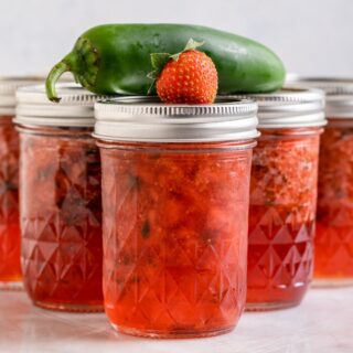 Homemade jam in jars with a pepper and strawberry on top