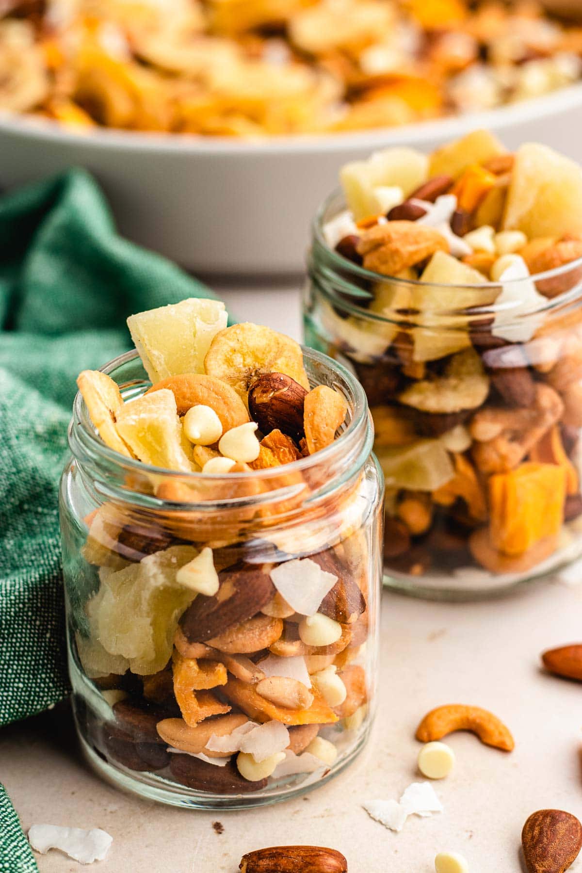 Tropical Trail Mix combined in glass jars and bowl of mix in background, side view