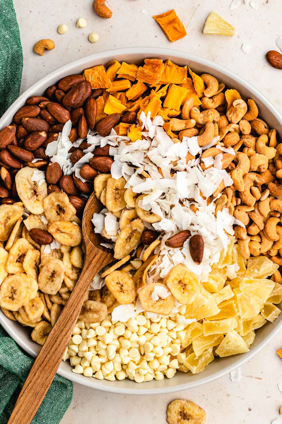 Tropical Trail Mix mixing in large bowl with wooden spoon, top down view