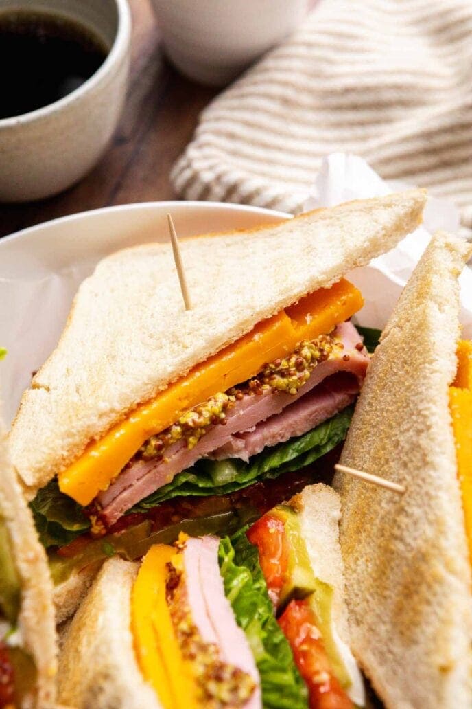 Two sandwiches sliced in half and piled on a plate