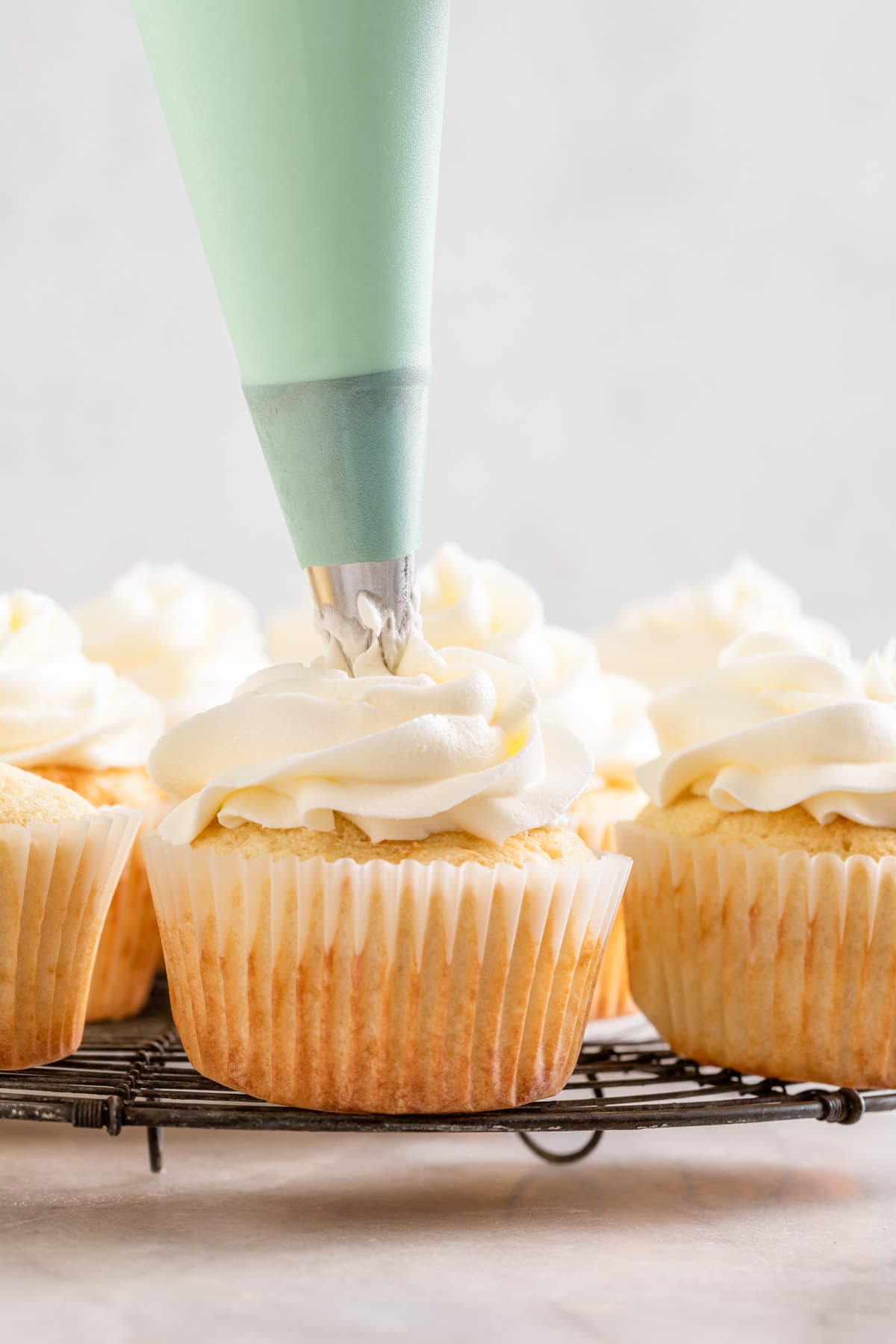 White Cupcakes Wedding Cupcakes piping frosting on cupcake on white rack