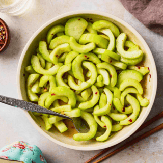 crunchy green veggies mixed with dressing in a white bowl and a spoon