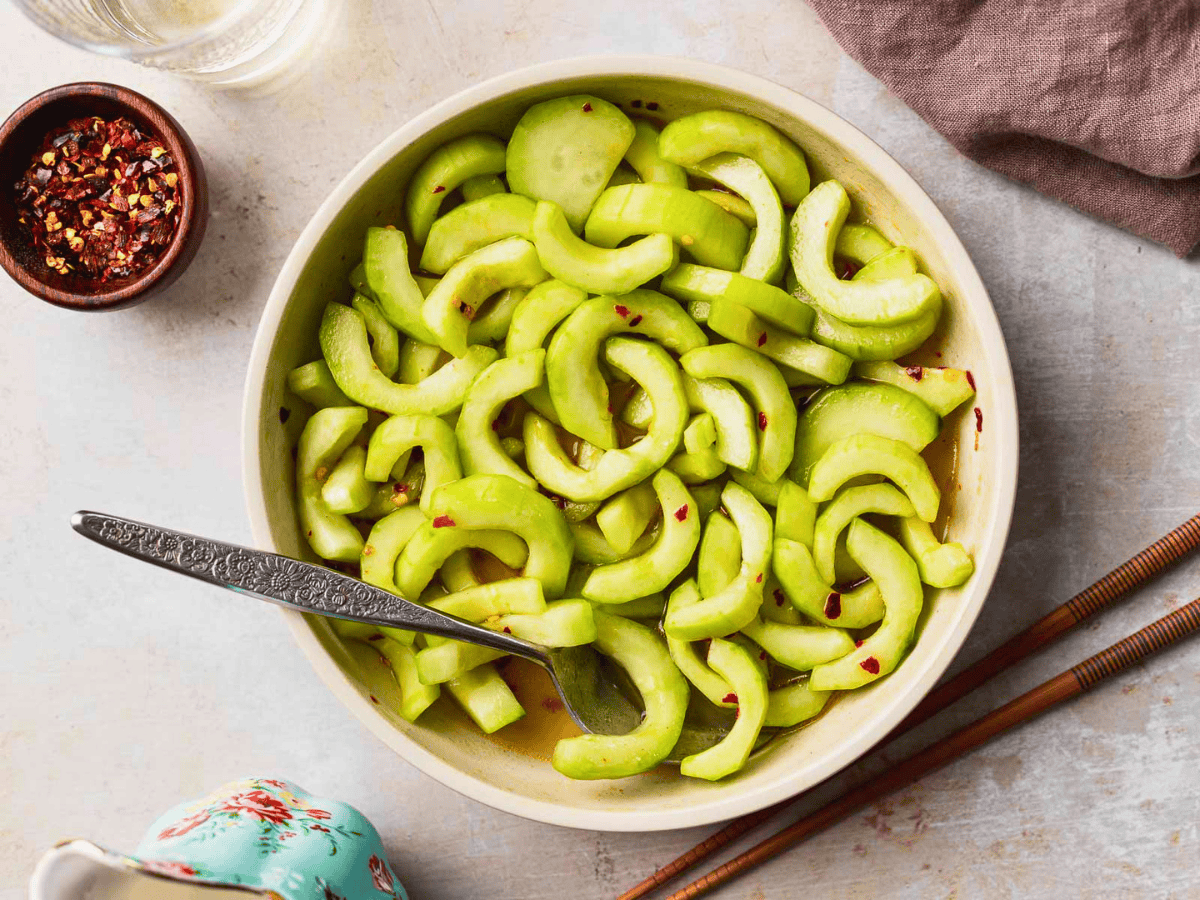 crunchy green veggies mixed with dressing in a white bowl and a spoon