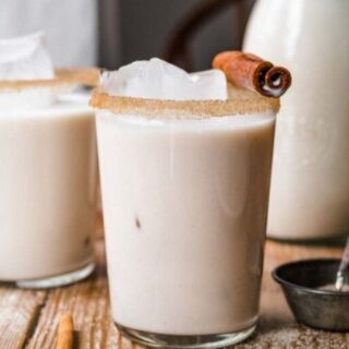 Drink in a glass with a cinnamon stick on top of the glass