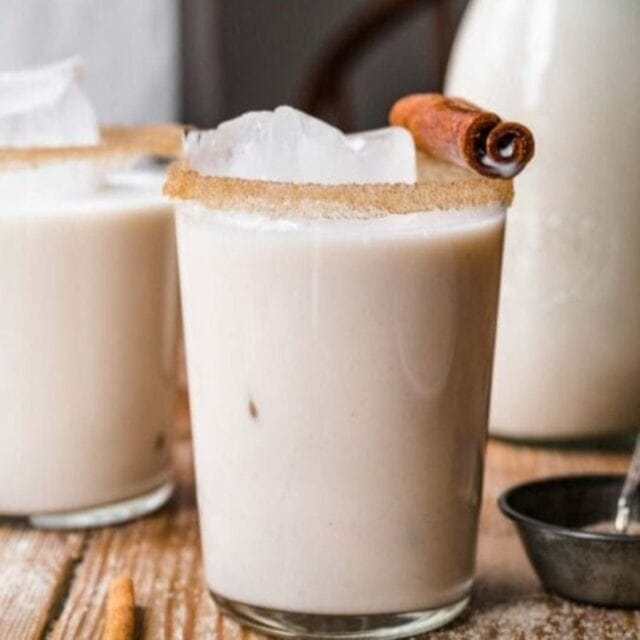 Drink in a glass with a cinnamon stick on top of the glass
