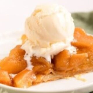 A slice of the tarte on a white plate with ice cream on top.