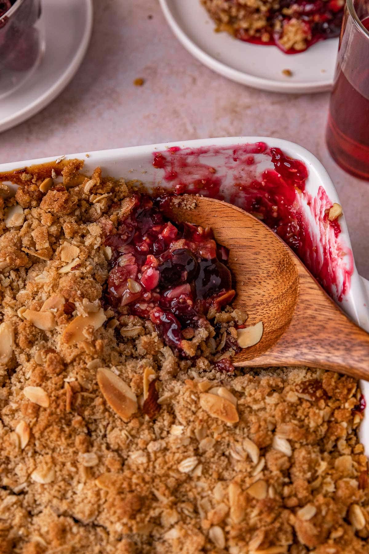 Cherry Crisp baked in pan with wooden spoon scooping out some filling
