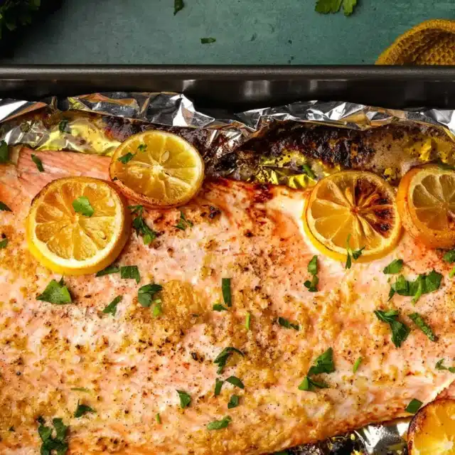 salmon with lemons on top on a sheet tray
