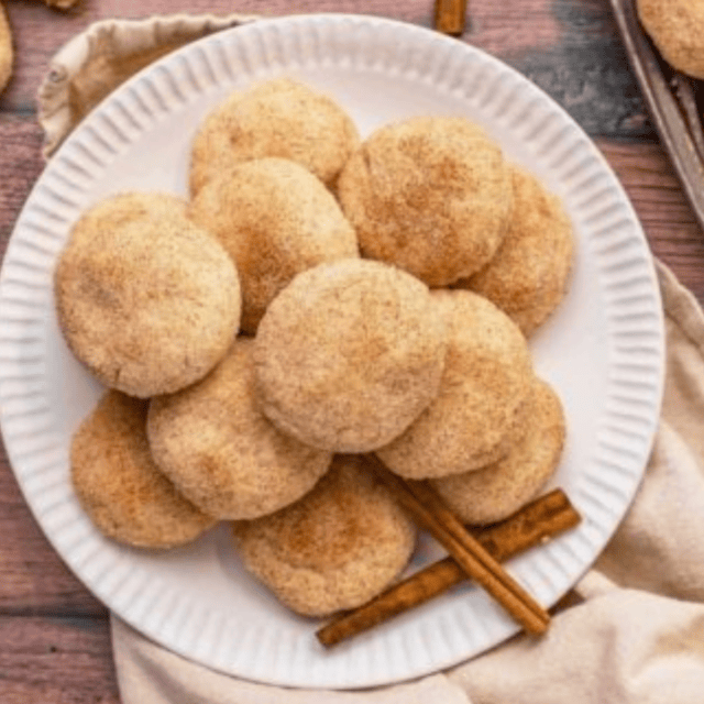 Cinnamon cookies on a white plate with cinnamon sticks