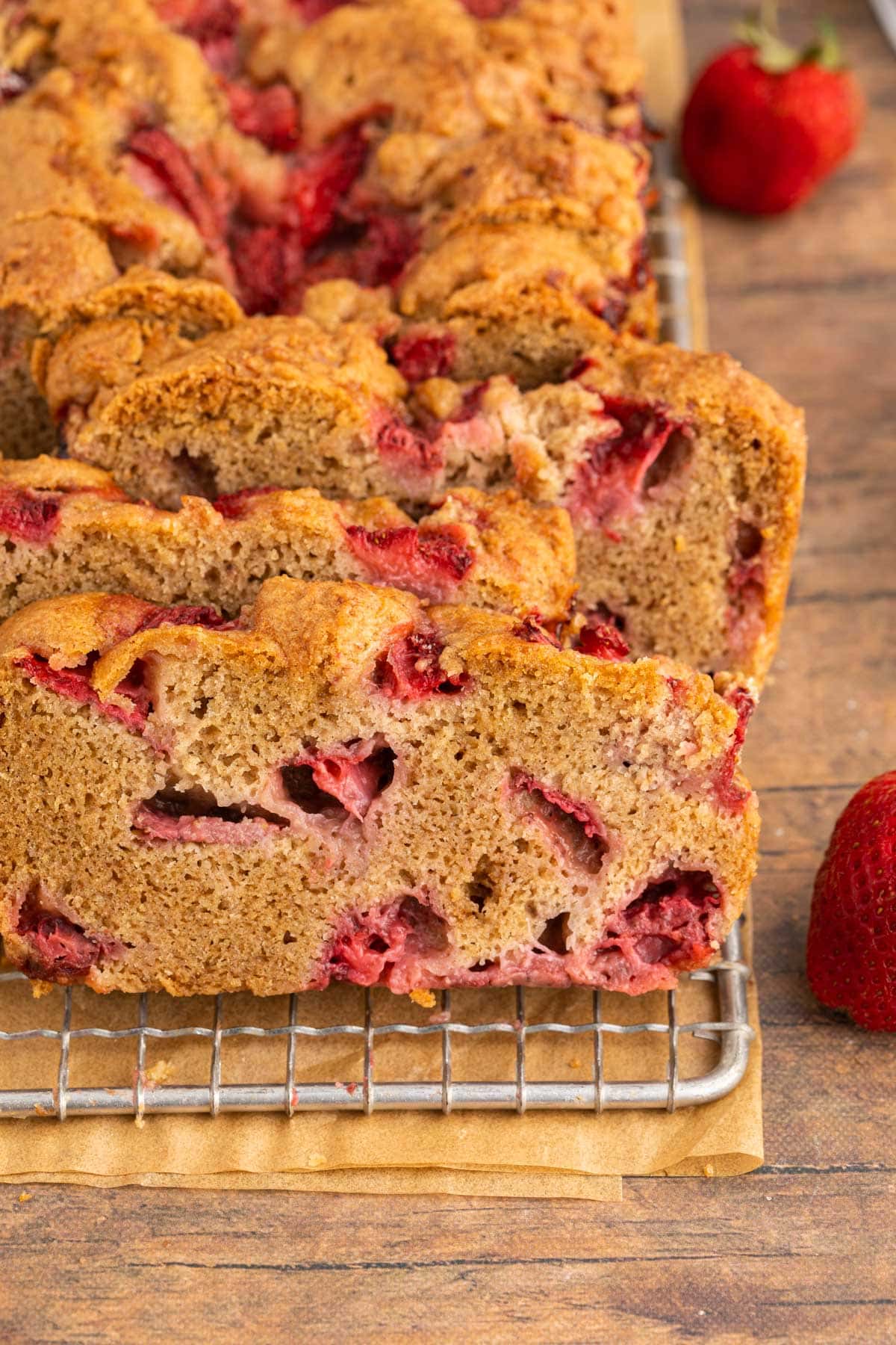 Strawberry Bread loaf half sliced and half unsliced loaf behind slices on wire rack