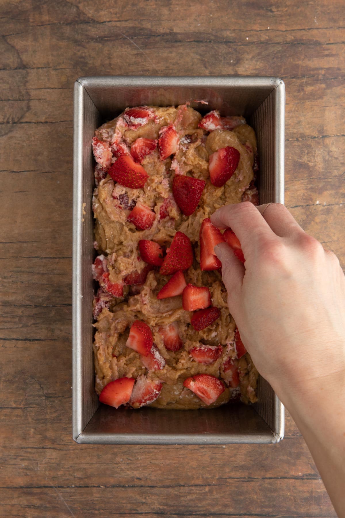 Strawberry Bread batter in loaf pan, placing strawberry slices on top