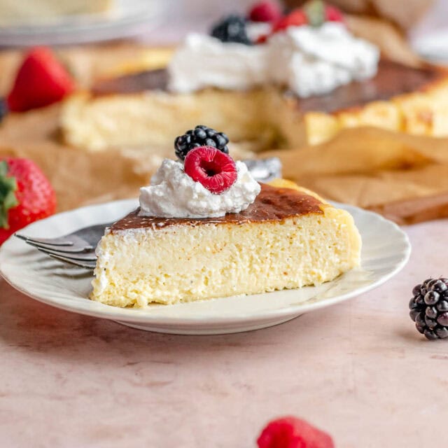 Slice of cheesecake on plate topped with whipped cream and berries.