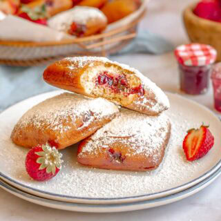 Sugar dusted fried pastries on plate with jelly.