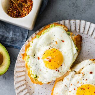 Avocado toast with egg on top on plate.