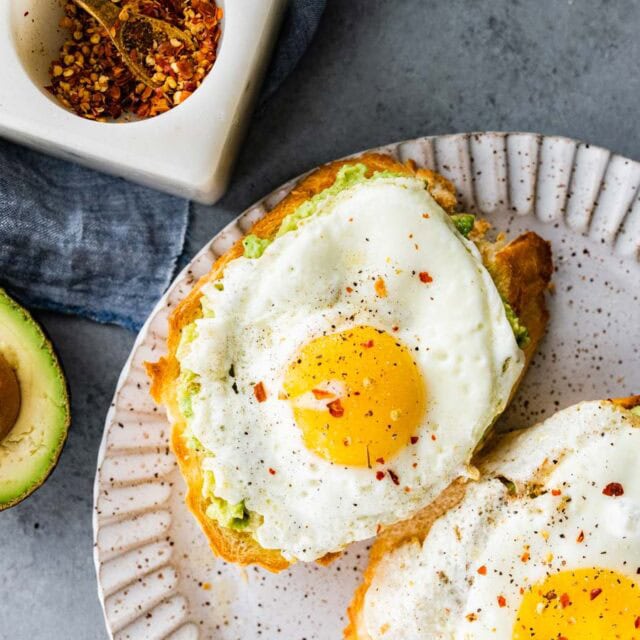 Avocado toast with egg on top on plate.