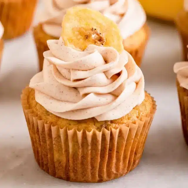 close up of individual sweet treat with frosting and tropical fruit on top