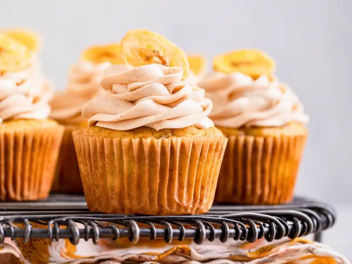 side view of individual sweet treats with frosting and tropical fruit on top side by side one another