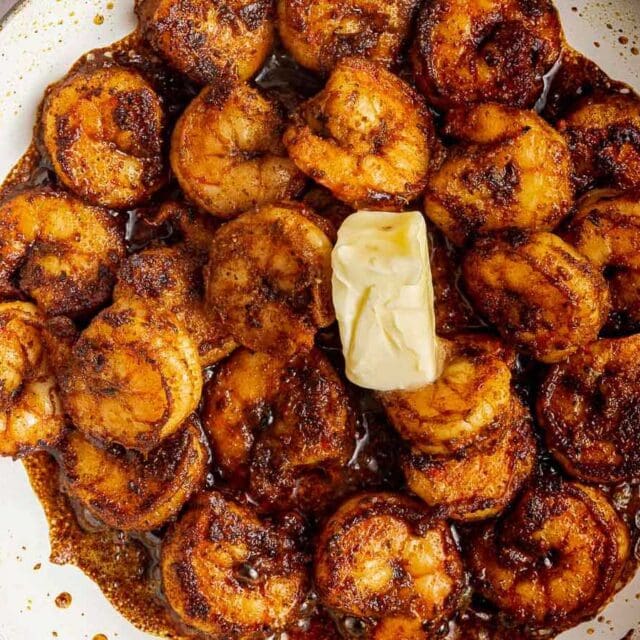 Cooked blackened seasoned shrimp in sauté pan with butter.