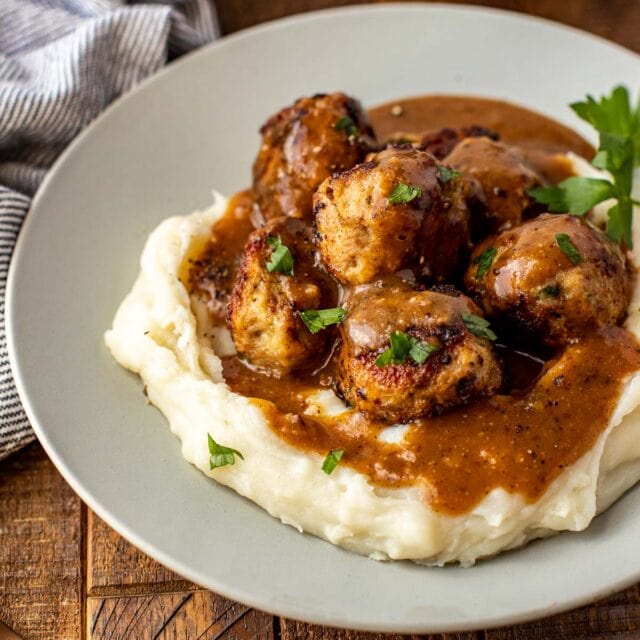Dinner plate with mashed potatoes, meatballs, and gravy.