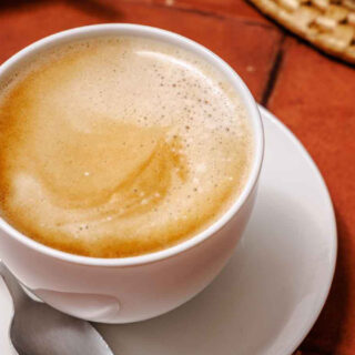 Café con leche in coffee cup with saucer
