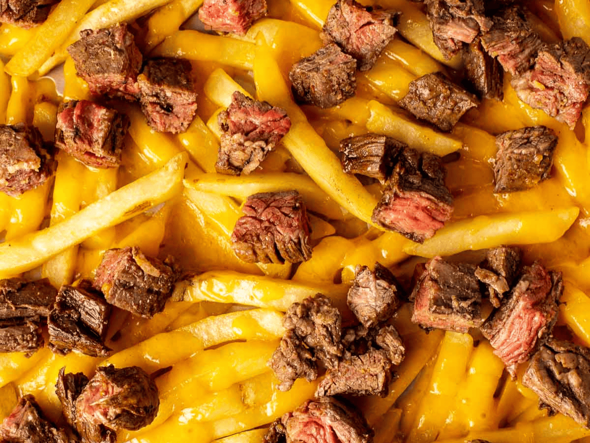 Close up of French fries with melted cheese and beef.