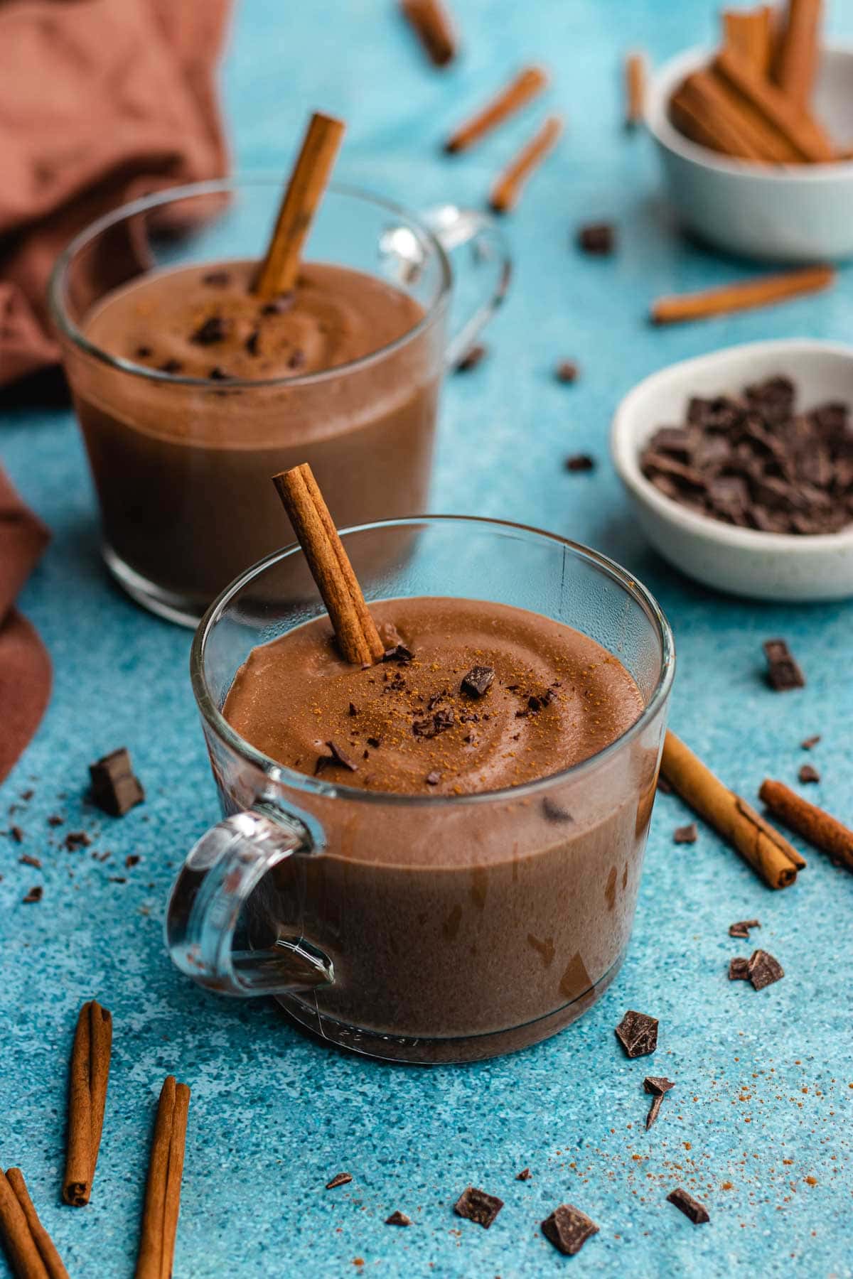 Champurrado finished drink in two glass coffee cup with cinnamon stick