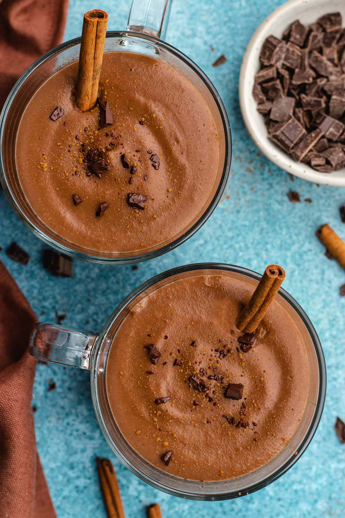 Champurrado finished drink in two glass coffee cups with cinnamon stick, top view