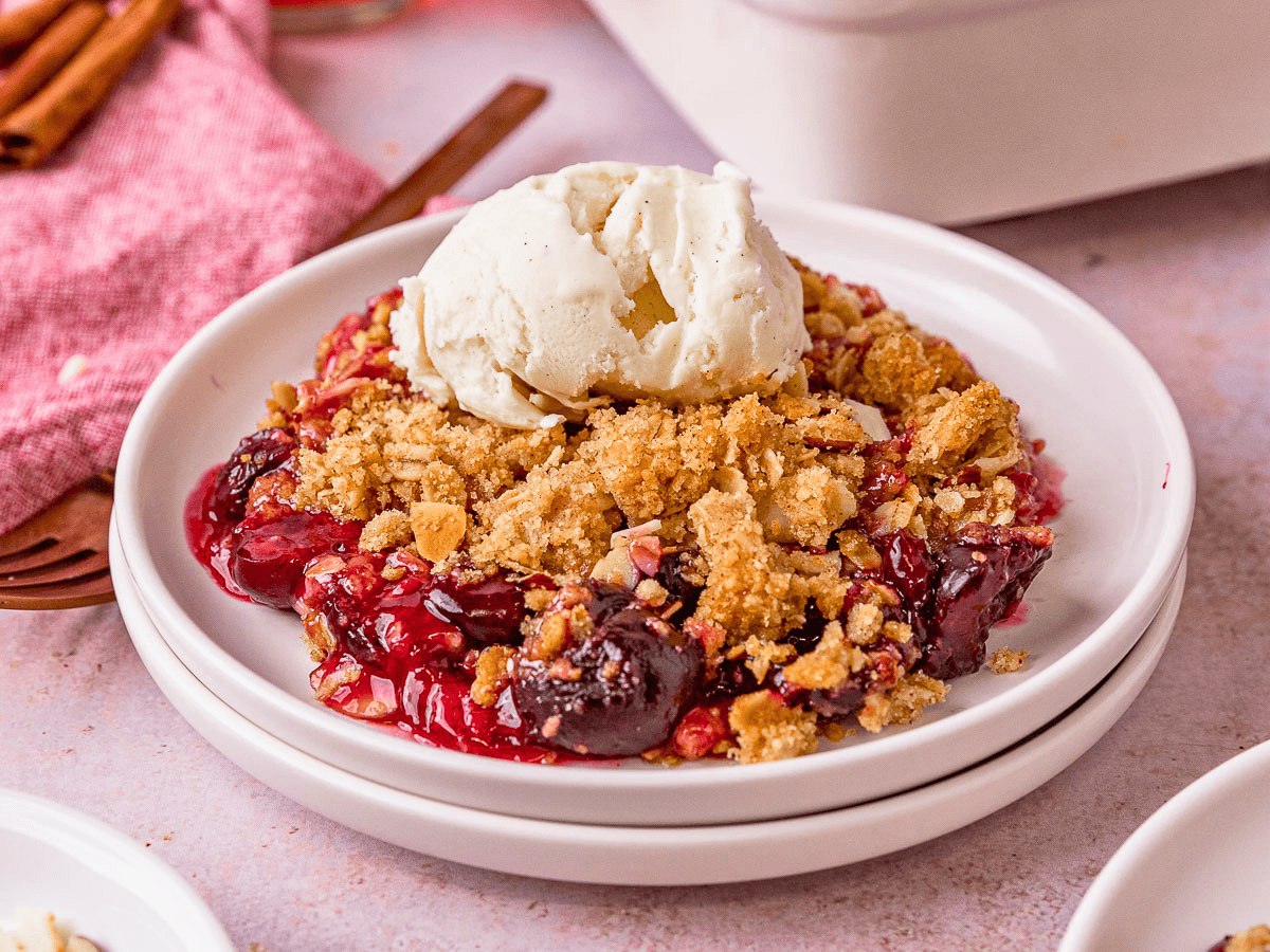 cherries, crunchy oats, and ice cream on top of a white plate 