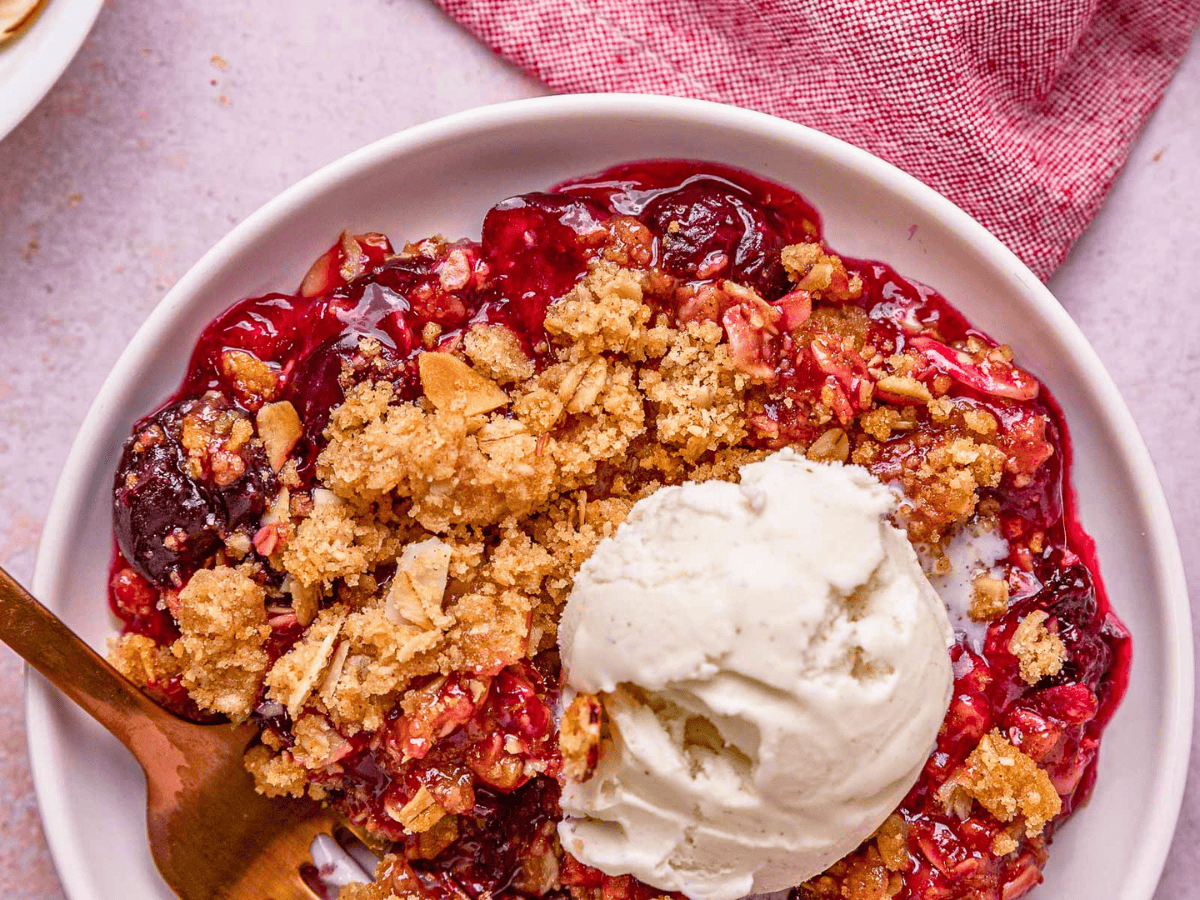 aerial view of cherries, oats, and almonds with a scoop of ice cream on a white plate